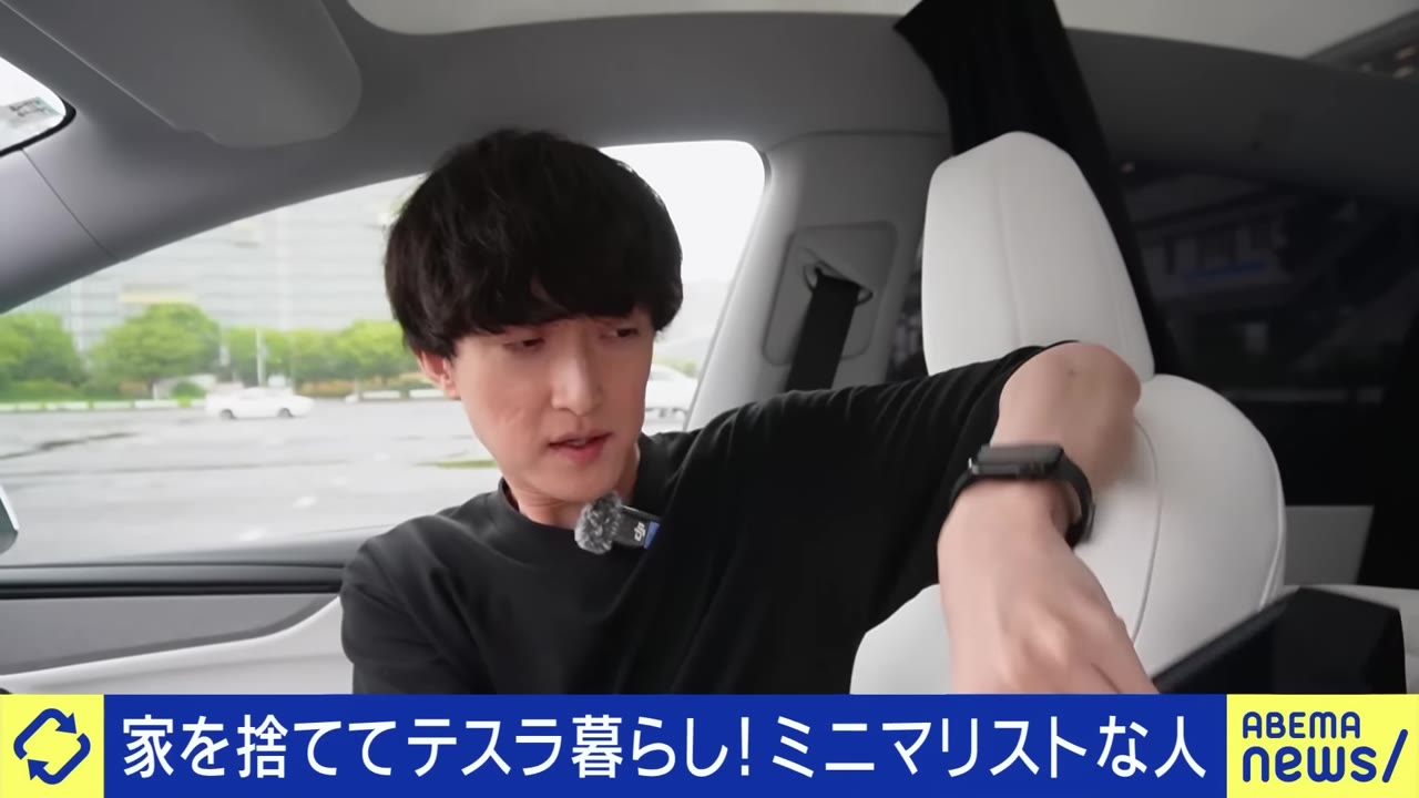 運転席の肘掛けにフィットする、テスラ専用の折りたたみデスク。引用：ABEMA Prime