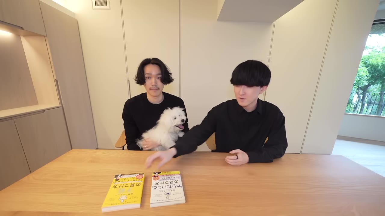 テーブルの上に置かれた2冊の著書と、犬を抱く八木さん